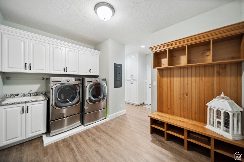 Laundry area with cabinets, sink, light wood-type flooring, and washer and clothes dryer