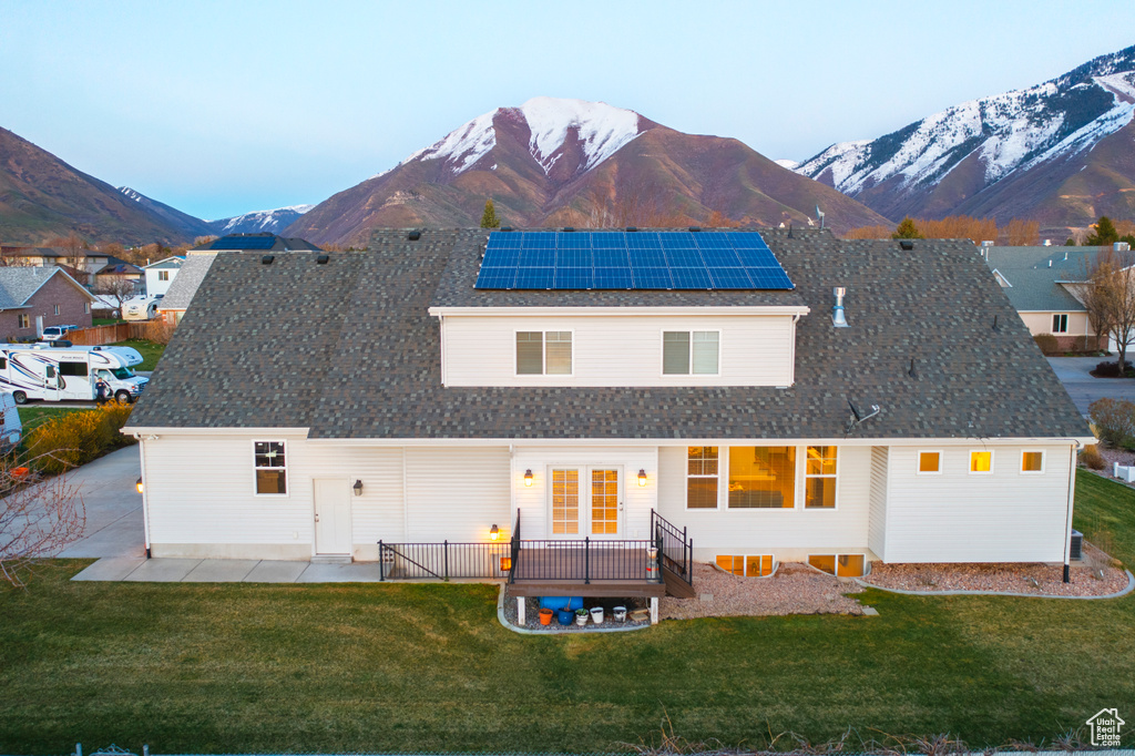 Back of house featuring solar panels, a patio area, a mountain view, french doors, and a lawn