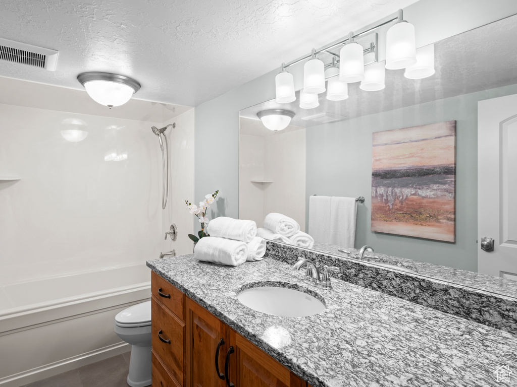 Full bathroom with toilet, oversized vanity, bathing tub / shower combination, a textured ceiling, and tile flooring