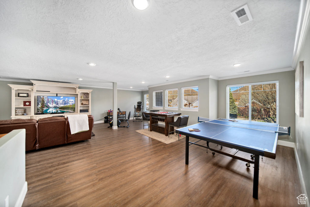 Game room with ornamental molding, a textured ceiling, and dark hardwood / wood-style flooring