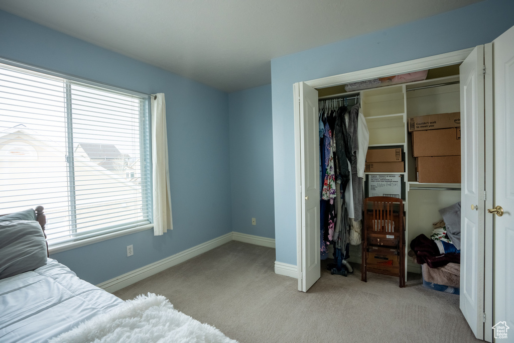 Bedroom with a closet, light colored carpet, and multiple windows