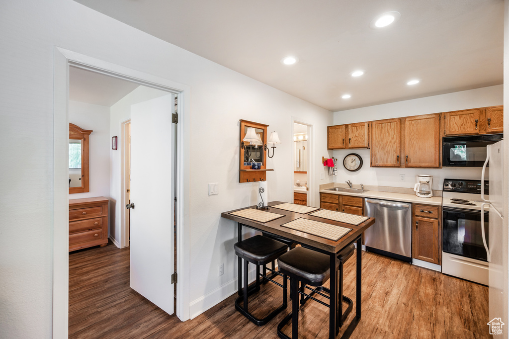 Kitchen with white electric range, sink, dishwasher, and dark hardwood / wood-style flooring
