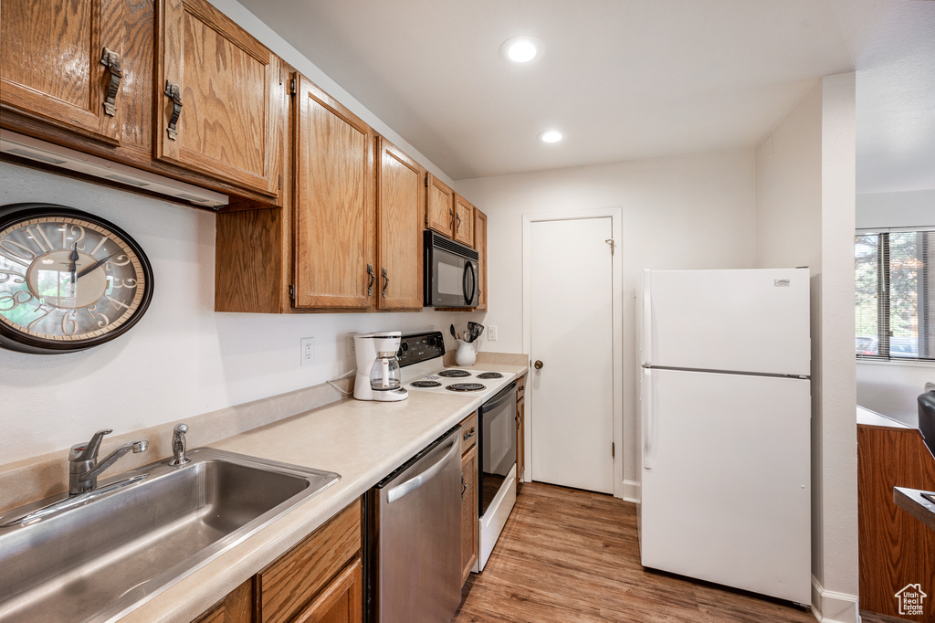 Kitchen with light wood-type flooring, range, dishwasher, sink, and white refrigerator