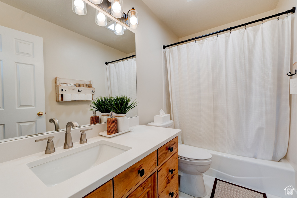 Full bathroom with oversized vanity, toilet, shower / bath combo, and tile floors