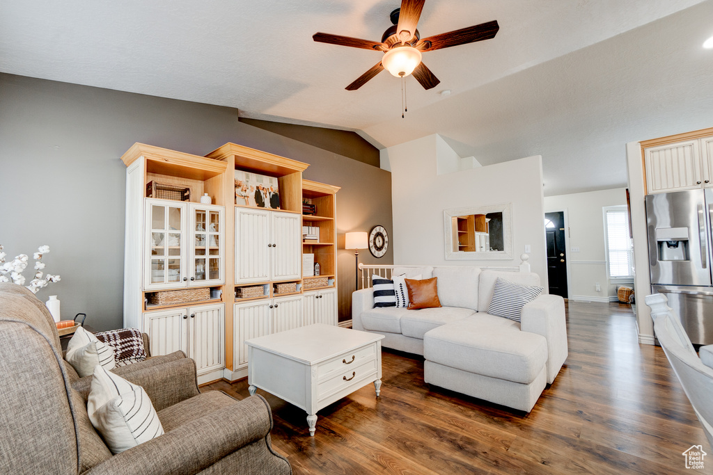 Living room featuring ceiling fan, dark hardwood / wood-style floors, and vaulted ceiling
