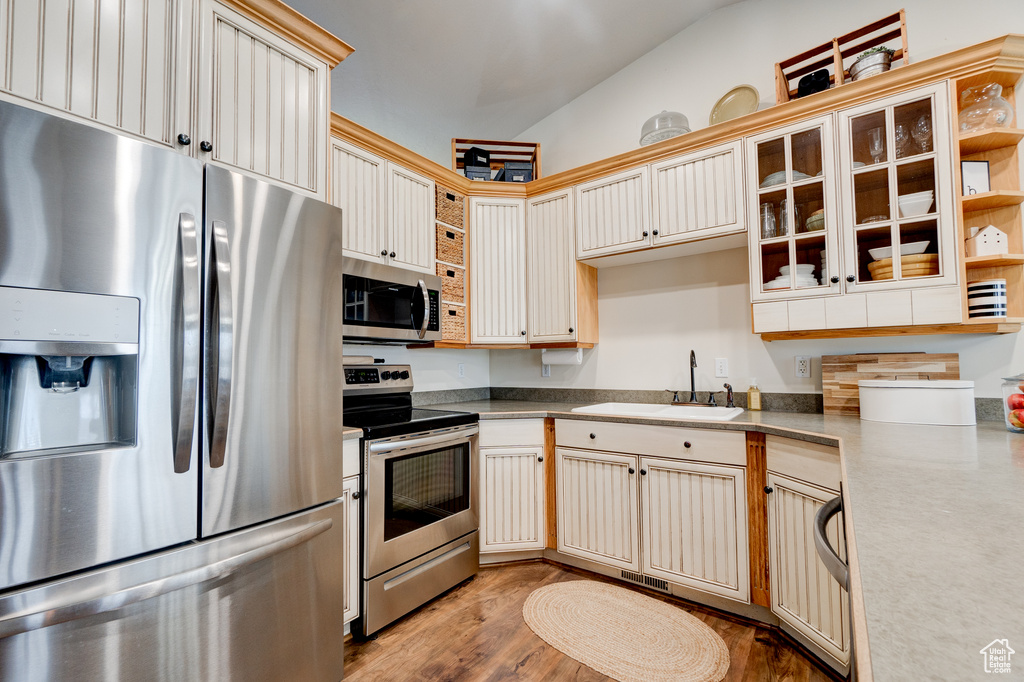 Kitchen featuring lofted ceiling, sink, appliances with stainless steel finishes, and light hardwood / wood-style flooring
