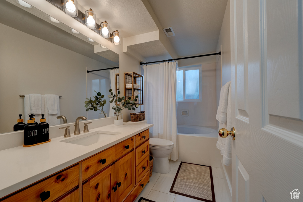 Full bathroom featuring shower / bath combo with shower curtain, toilet, large vanity, and tile floors