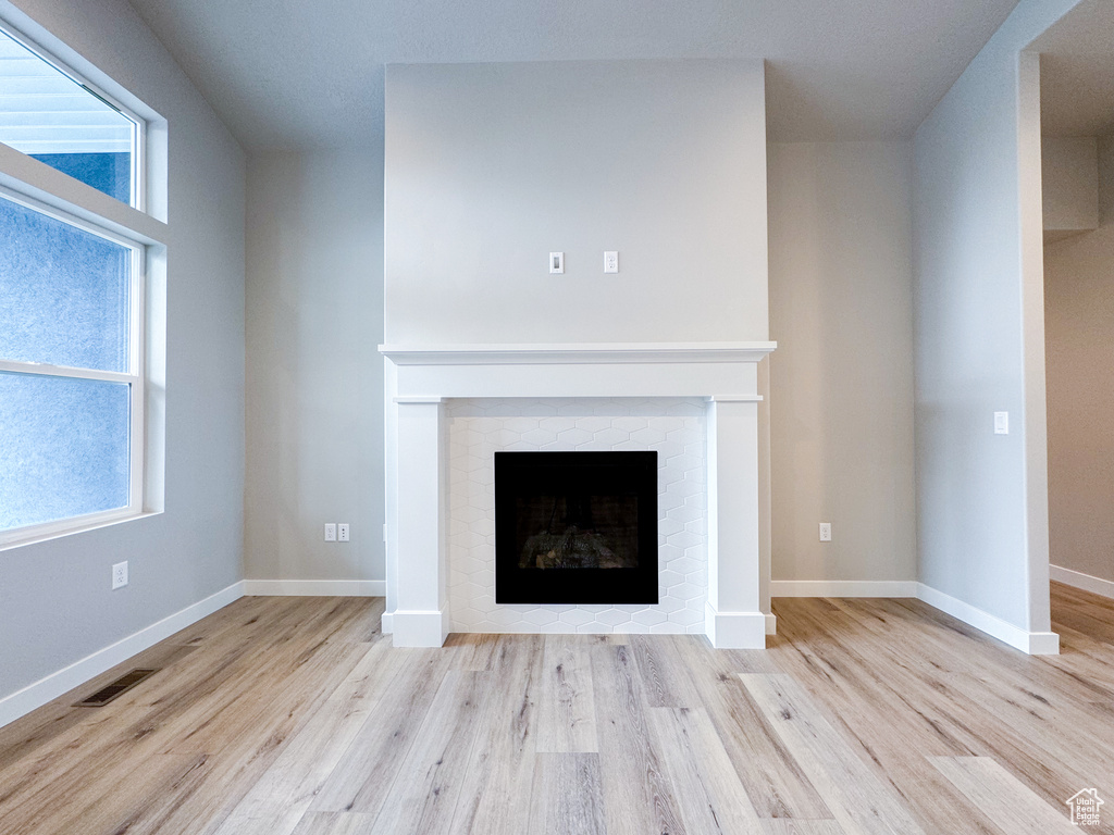 Unfurnished living room with a brick fireplace and light wood-type flooring
