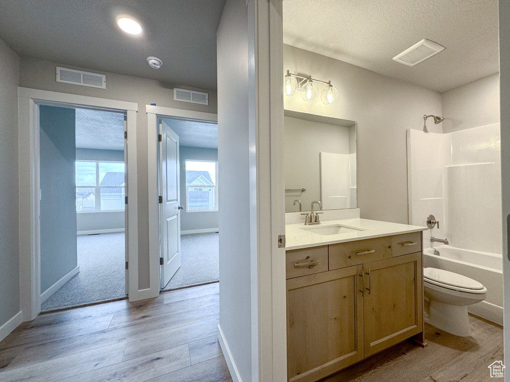Full bathroom featuring washtub / shower combination, large vanity, a textured ceiling, toilet, and hardwood / wood-style flooring