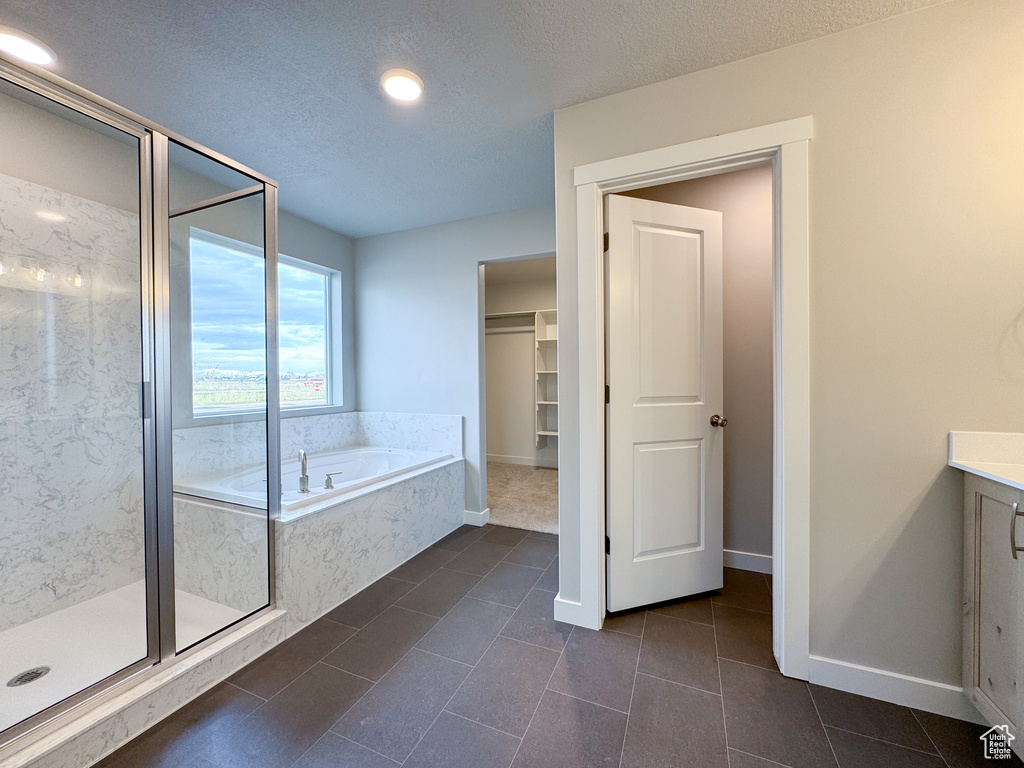 Bathroom featuring a textured ceiling, tile flooring, vanity, and independent shower and bath