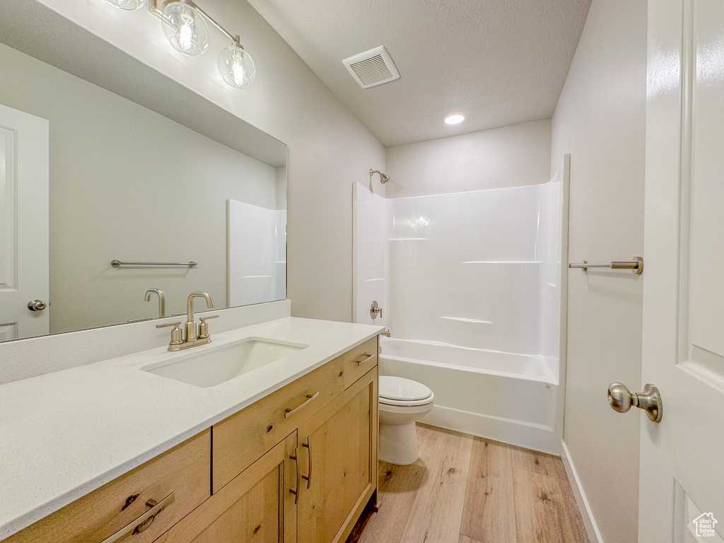 Full bathroom featuring shower / washtub combination, toilet, vanity, and wood-type flooring