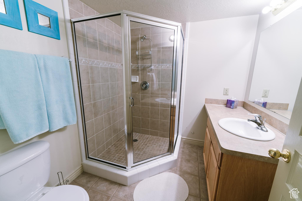 Bathroom featuring a shower with door, tile flooring, oversized vanity, and toilet