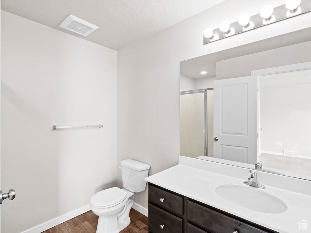 Bathroom featuring toilet, vanity with extensive cabinet space, and hardwood / wood-style flooring