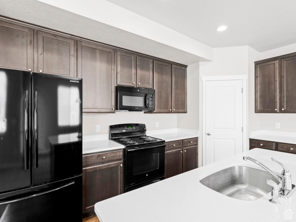 Kitchen featuring dark brown cabinets, black appliances, and sink