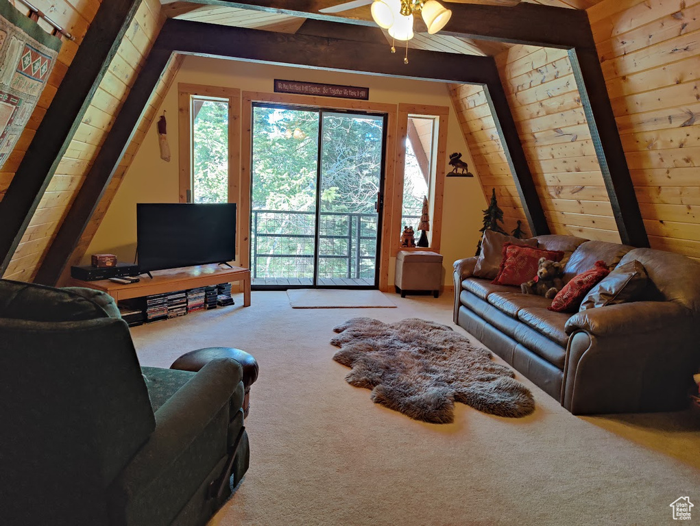 Carpeted living room with ceiling fan, beam ceiling, and wooden walls