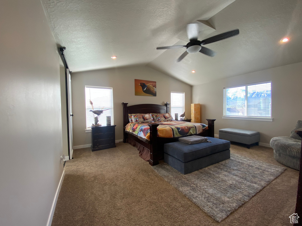 Carpeted bedroom featuring a textured ceiling, ceiling fan, and vaulted ceiling