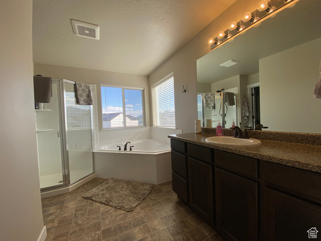 Bathroom featuring tile floors, independent shower and bath, oversized vanity, and a textured ceiling