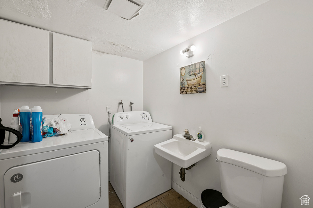 Washroom with sink, independent washer and dryer, and light tile flooring