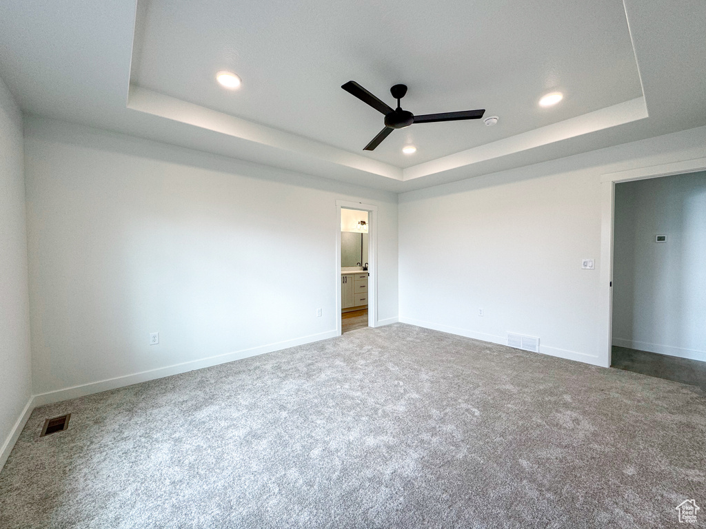 Unfurnished room with ceiling fan, carpet flooring, and a raised ceiling