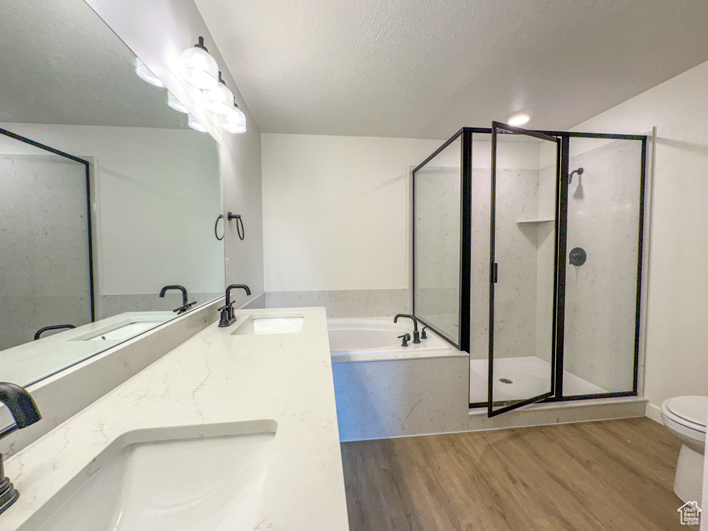 Full bathroom with toilet, wood-type flooring, dual sinks, oversized vanity, and separate shower and tub