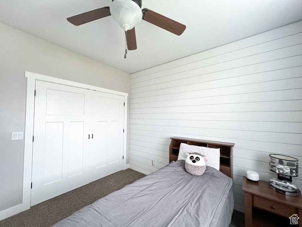 Bedroom featuring a closet, ceiling fan, and dark colored carpet