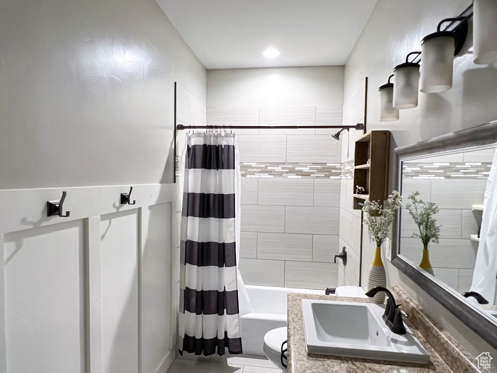 Full bathroom featuring toilet, shower / bathtub combination with curtain, and sink