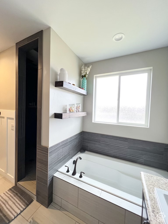 Bathroom with tiled bath, tile flooring, and vanity