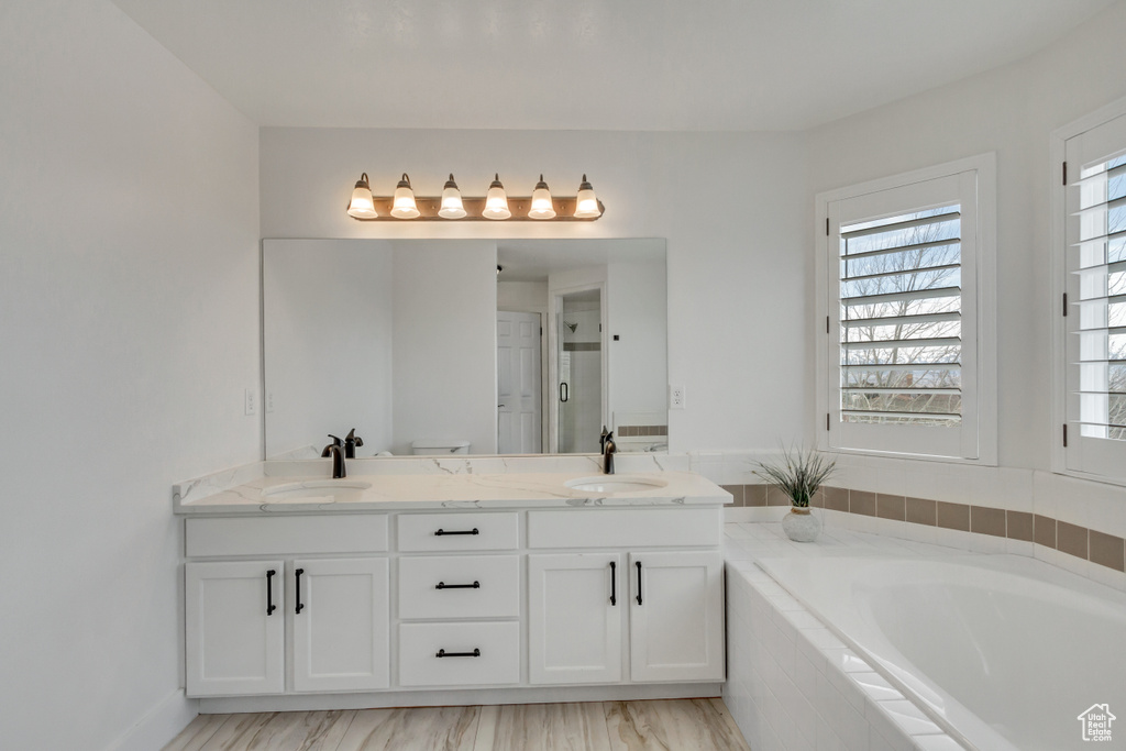 Bathroom with double sink, vanity with extensive cabinet space, and tiled tub