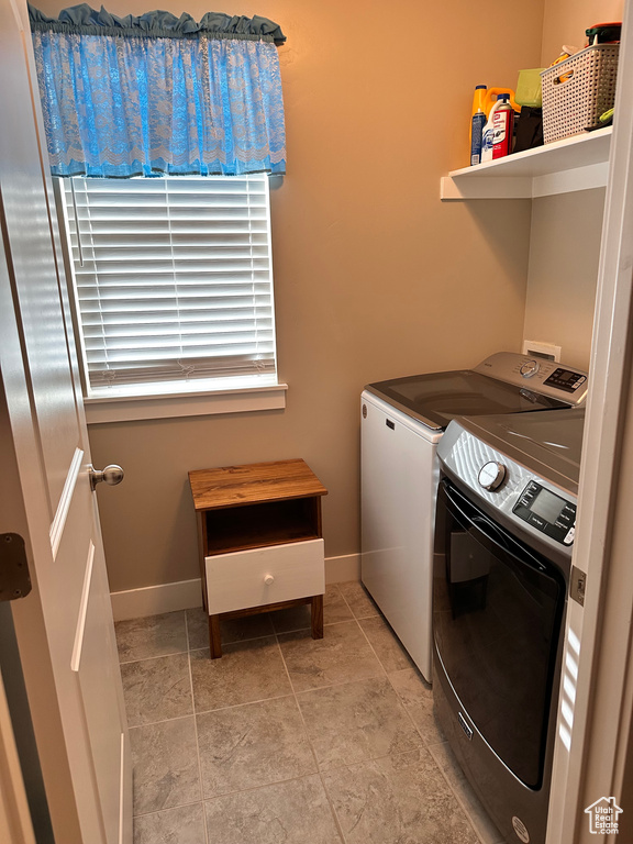 Laundry area with washer hookup, light tile floors, and washer and clothes dryer