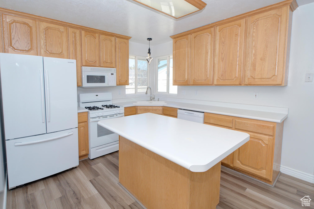 Kitchen with light wood-type flooring, white appliances, sink, and a center island
