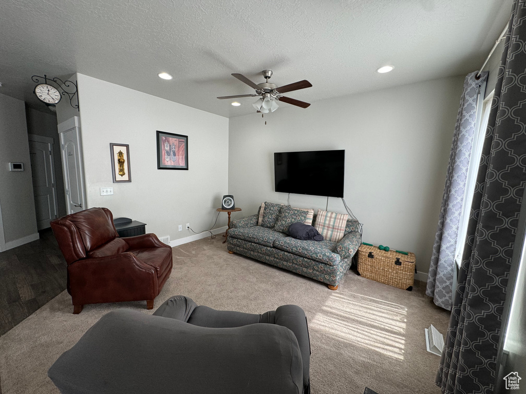 Living room with carpet flooring, ceiling fan, and a textured ceiling