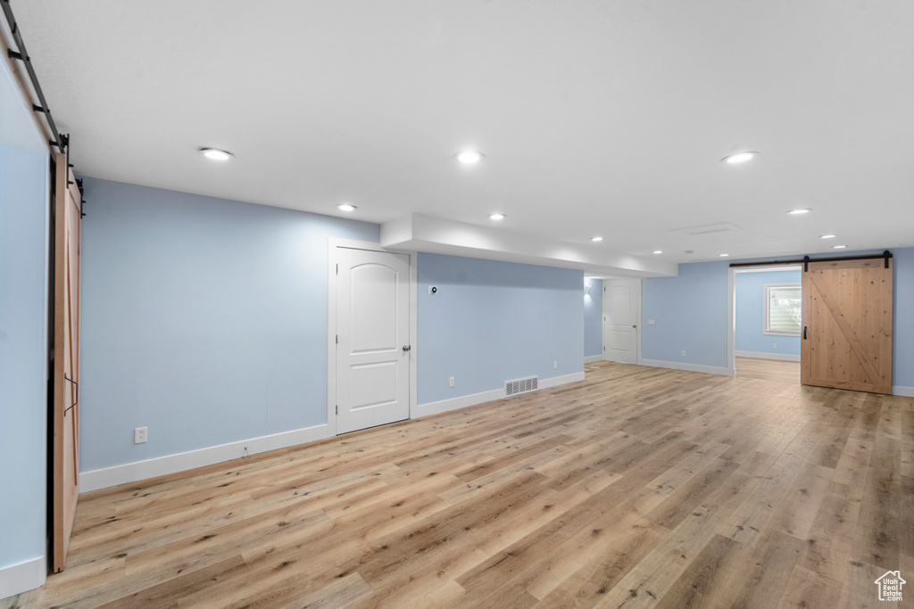 Basement featuring light wood-type flooring and a barn door