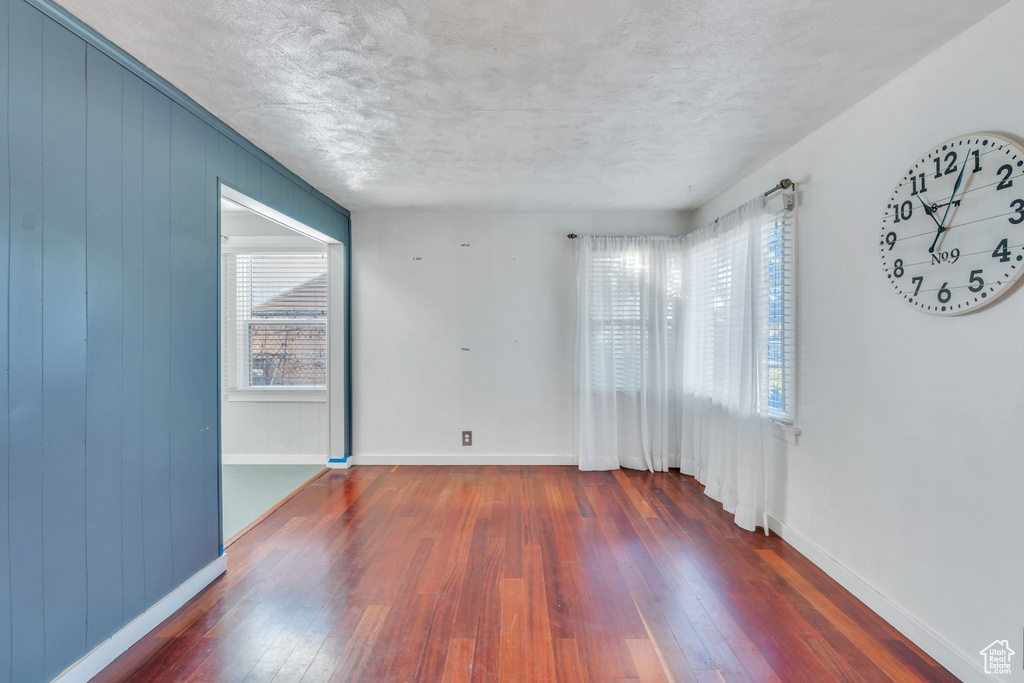 Unfurnished room featuring a wealth of natural light, dark hardwood / wood-style floors, and a textured ceiling