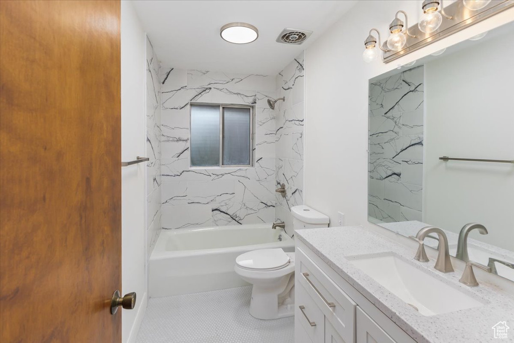 Full bathroom featuring tiled shower / bath, toilet, vanity with extensive cabinet space, and tile floors
