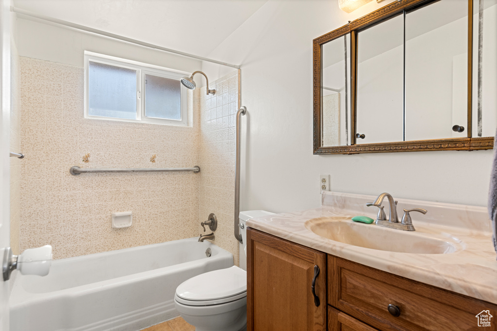 Full bathroom with toilet, tiled shower / bath combo, and vanity
