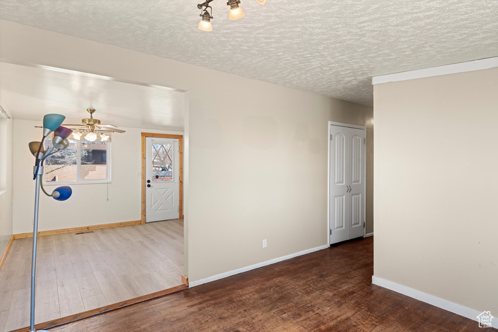 Empty room with dark hardwood / wood-style flooring, ceiling fan, and a textured ceiling