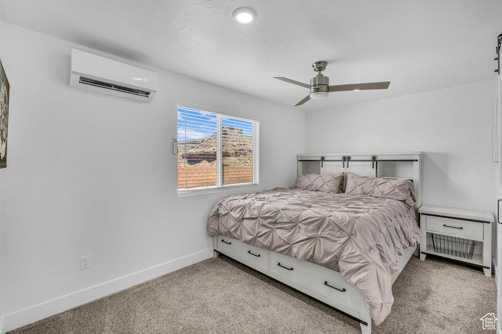 Bedroom with an AC wall unit, ceiling fan, and light colored carpet