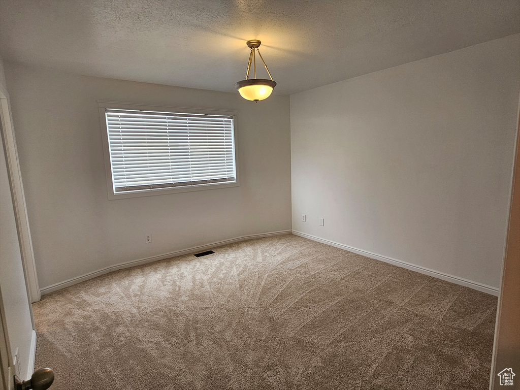 Empty room featuring a textured ceiling and dark colored carpet