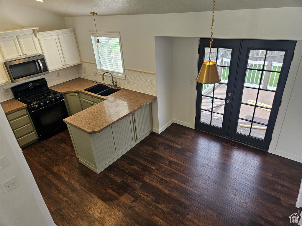 Kitchen featuring dark hardwood / wood-style floors, kitchen peninsula, range with gas stovetop, and sink