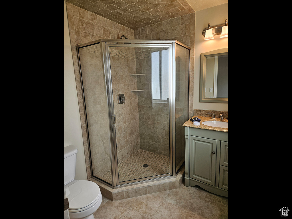 Bathroom with an enclosed shower, tile floors, vanity with extensive cabinet space, and toilet