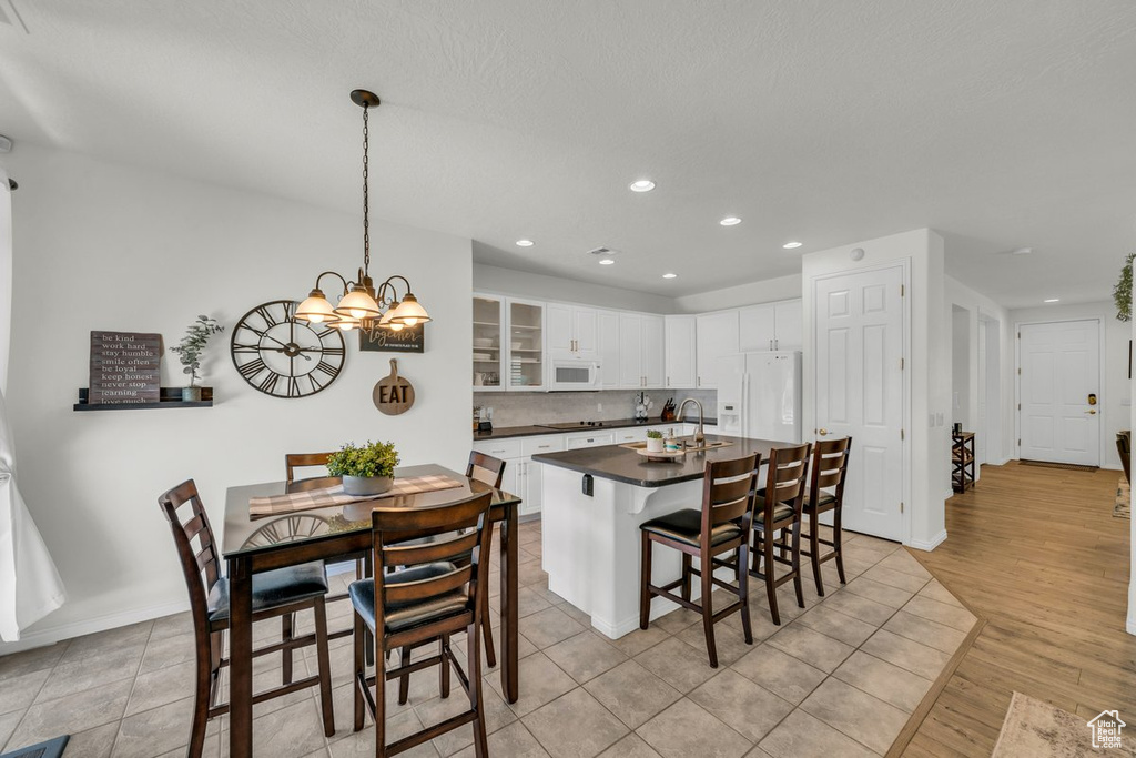 Kitchen with a chandelier, white cabinets, a kitchen bar, light hardwood / wood-style flooring, and white appliances