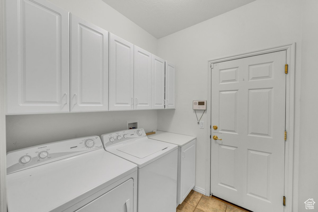 Laundry room featuring cabinets, washer and clothes dryer, washer hookup, and light tile floors