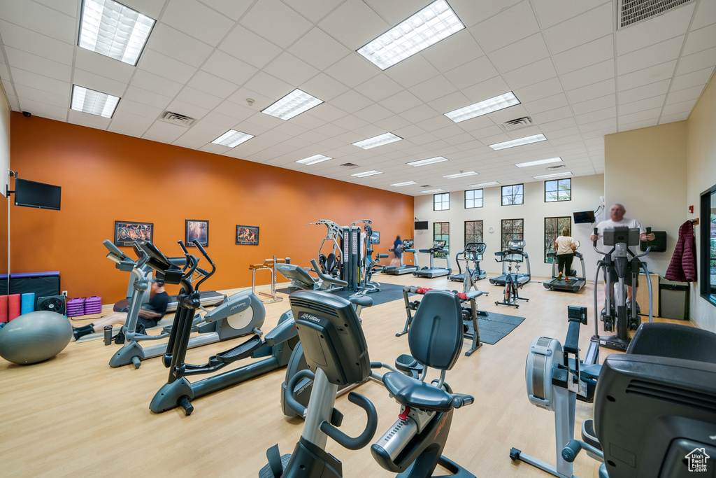 Workout area with light hardwood / wood-style flooring and a drop ceiling