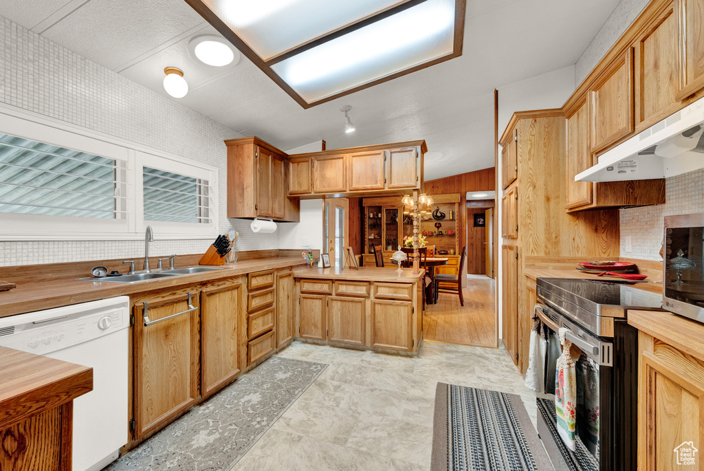 Kitchen with electric stove, sink, light tile floors, white dishwasher, and a notable chandelier