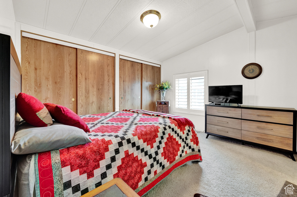 Carpeted bedroom with multiple closets and lofted ceiling