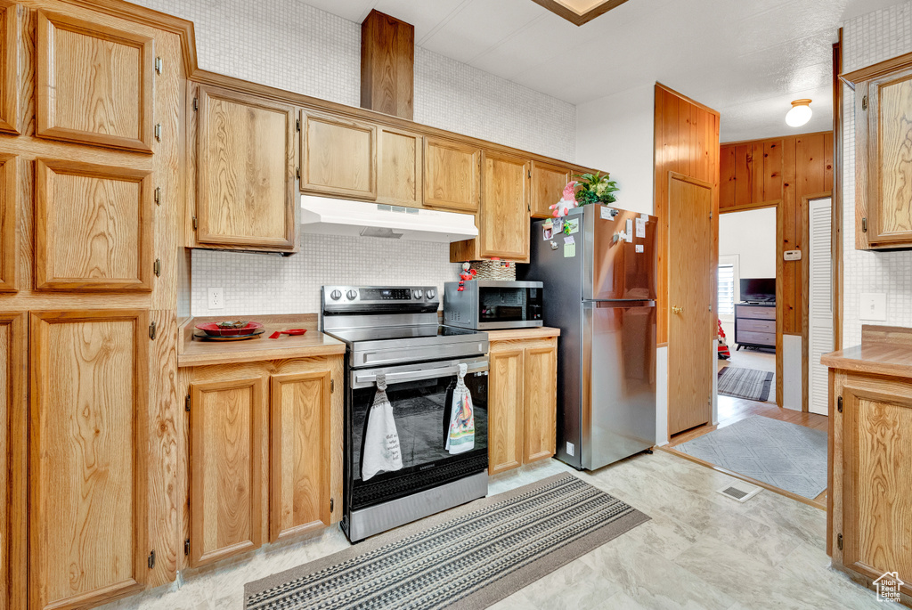 Kitchen with appliances with stainless steel finishes, backsplash, and light tile floors