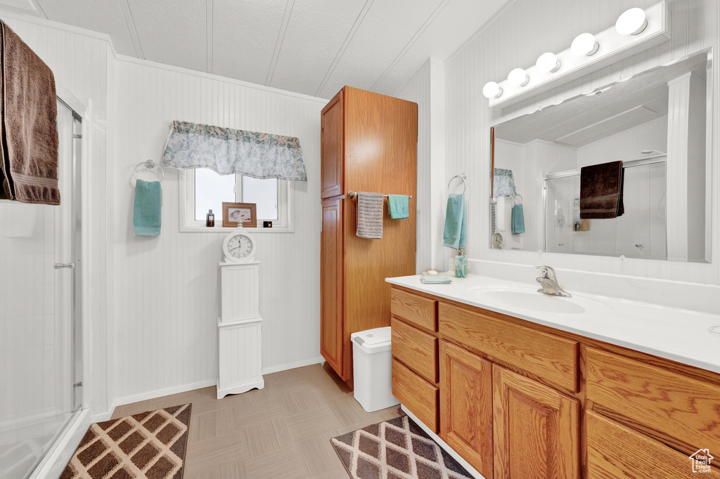 Bathroom with lofted ceiling, a shower with shower door, and vanity with extensive cabinet space
