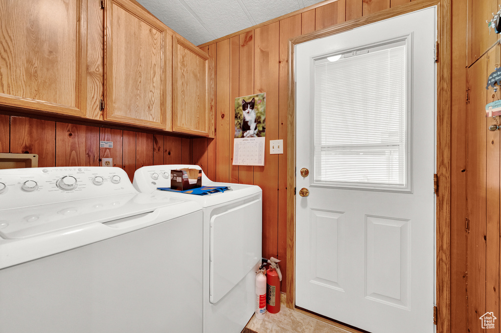 Laundry room with separate washer and dryer, cabinets, and wooden walls