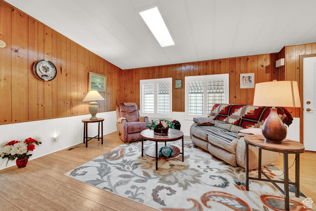 Living room featuring light hardwood / wood-style floors, wooden walls, and lofted ceiling