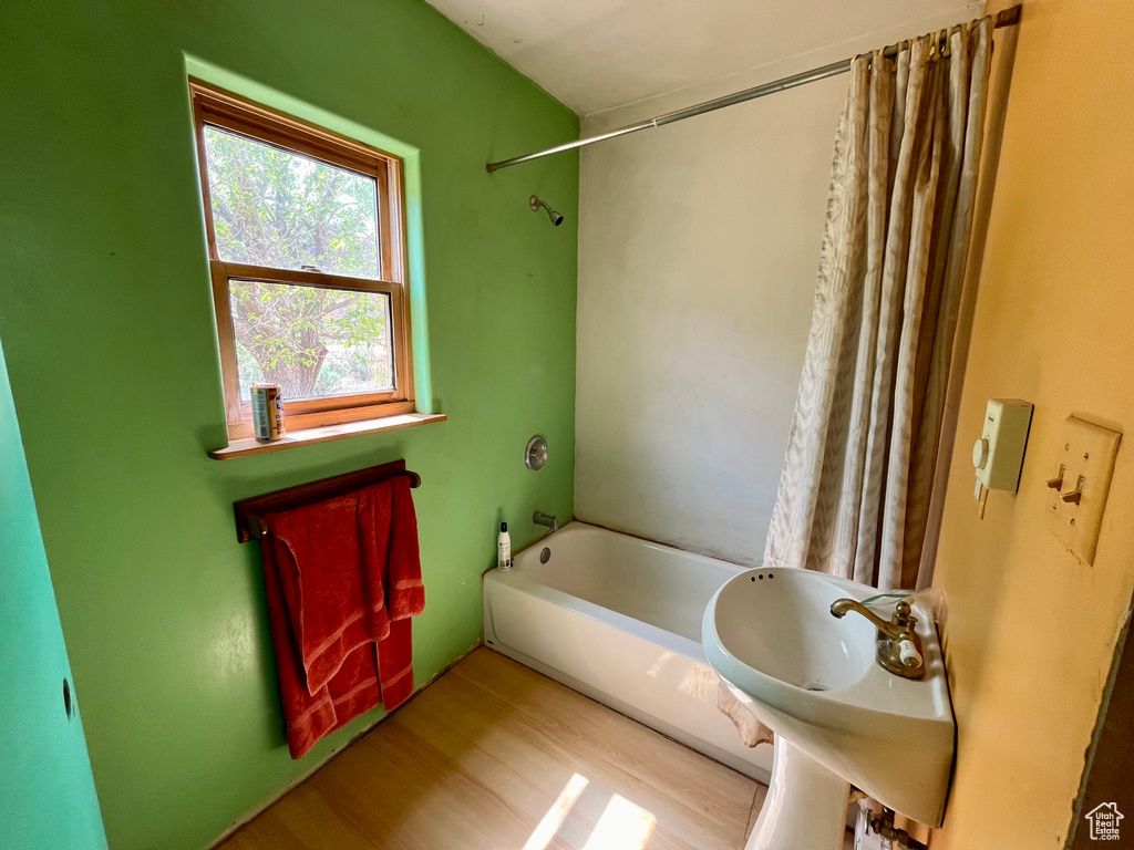 Bathroom with sink, hardwood / wood-style floors, and shower / bathtub combination with curtain